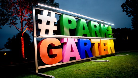 Ein illuminierter Schriftzug steht im Park der Gärten auf einer Rasenfläche. © dpa-Bildfunk Foto: Hauke-Christian Dittrich