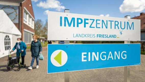 Zwei ältere Damen gehen vor dem Impfzentrum Landkreis Friesland entlang. © Picture Alliance Foto: Mohssen Assanimoghaddam