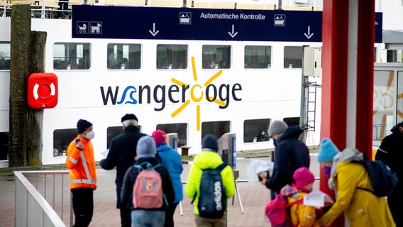 Touristen werden im Fährhafen vor der Überfahrt zur Insel Wangerooge auf ihr Ticket und einen negativen Corona-Test kontrolliert. © dpa-Bildfunk Foto: Hauke-Christian Dittrich