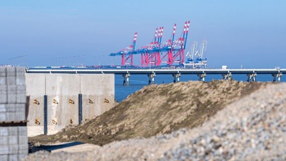 Der Jade-Weser-Port ist hinter einer Baustelle am Deich zu sehen. © dpa-Bildfunk Foto: Sina Schuldt
