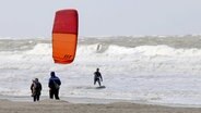 Ein Kitesurfer ist bei stürmischem Wetter vor der Insel Norderney unterwegs. © Volker Bartels/dpa +++ dpa-Bildfunk +++ Foto: Volker Bartels