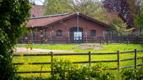 Stacheldrahtzäune, Sichtschutzwände und Überwachungskameras sichern eine Reithalle, die zum Gerichtssaal umgebaut wird. © dpa Foto: Sina Schuldt