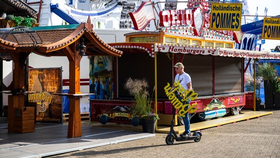 Oldenburg: Ein Schausteller fährt einen Schriftzug auf einem E-Roller zu seinem Stand. Auf dem Festplatz vor der Weser-Ems-Halle wird der Oldenburger Kramermarkt aufgebaut. Der 416. Kramermarkt wird am 30. September mit dem traditionellen Festumzug offiziell eröffnet. © Sina Schuldt/dpa/dpa-Bildfunk Foto: Sina Schuldt