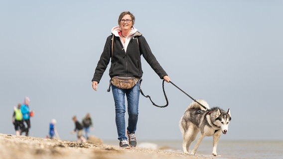 Ein Frau geht mit einem Hund an einem Strand spazieren. © dpa-Bildfunk Foto: Mohssen Assanimoghaddam