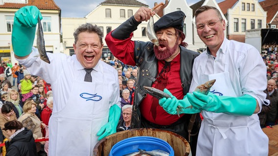 Andreas Philippi (SPD),  Schauspieler Bernd Maas in der Rolle des Seeräubers Klaus Störtebeker und Frank Imhoff (CDU) posieren bei der Lätare-Spende für ein Foto. © dpa Foto: Focke Strangmann