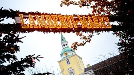 Ein leuchtender Schriftzug hängt über dem Eingang zum Lamberti-Markt vor dem Schloss. © dpa-Bildfunk Foto: Hauke-Christian Dittrich