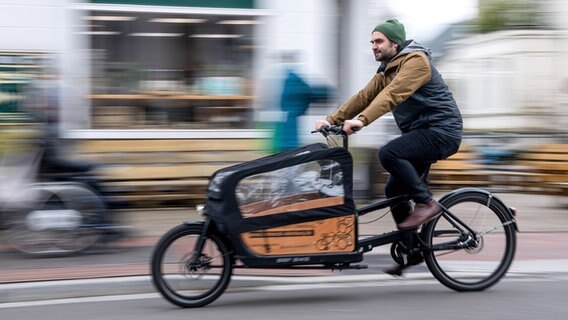 Ein Mann fährt mit einem Lastenrad. © picture alliance/dpa/Sina Schuldt Foto: Sina Schuldt