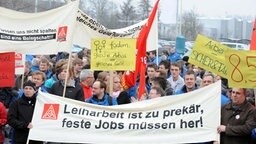 Eine Demonstration zum Thema Leiharbeit, im Vordergrund halten Menschen ein Transparent hoch. Eine Demonstration zum Thema Leiharbeit, im Vordergrund halten Menschen ein Transparent hoch. © dpa Foto: Ingo Wagner