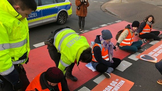 Vier Aktivisten der "Letzten Generation" sitzen auf einer Straße. © NDR Foto: Thomas Stahlberg