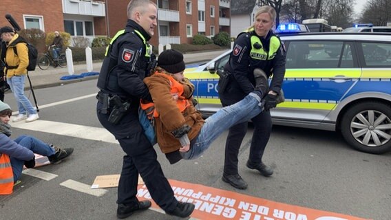 Eine Klimaaktivistin wird von Polizeibeamten während einer Blockade weggetragen. © NDR Foto: Anna Schlieter