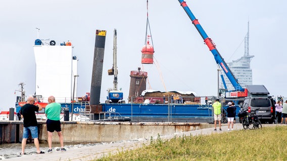 Passanten beobachten wie die Huppel vom schiefen Turm gehoben wird. © dpa-Bildfunk Foto: Hauke-Christian Dittrich/dpa