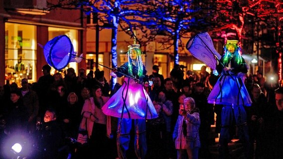 Zwei beleuchtete Stelzenläuferinnen gehen im Rahmen eines Lichtfestes durch die Innenstadt Wilhelmshaven. © dpa-Bildfunk Foto: Hauke-Christian Dittrich/dpa