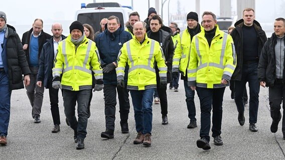 Robert Habeck (Bündnis 90/Die Grünen, r-l), Bundesminister für Wirtschaft und Klimaschutz, Bundeskanzler Olaf Scholz (SPD) und Christian Lindner (FDP), Bundesminister der Finanzen laufen auf einem Pier. © dpa-Bildfunk Foto: Sina Schuldt