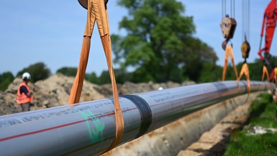 Ein Teilstück einer LNG-Pipeline wird in einen ausgehobenen Schacht gehoben. © picture alliance/dpa/Lars Penning Foto: Lars Penning