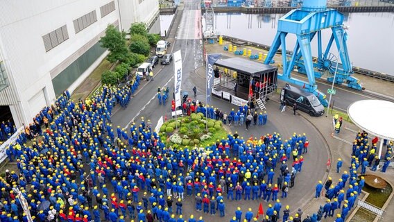 Mitarbeitende der Meyer Werft stehen für eine Kundgebung vor dem Werkstor. © dpa-Bildfunk Foto:  Sina Schuldt/dpa