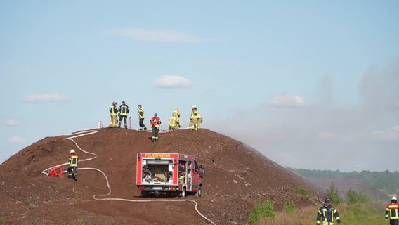 Feuerwehrleute stehen bei einem Einsatz auf einer Torfmiete. © Nord-West-Media TV 
