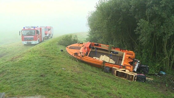 Ein beschädigtes Motorboot liegt am Flussufer neben einem Rettungswagen. © NonstopNews 