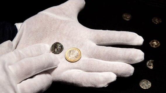 Carsten Eilts, ehrenamtlicher Sondengänger, hält während einer Pressekonferenz der Ostfriesischen Landschaft eine römische Münze und einen Euro zum Größenvergleich in den Händen. © dpa-Bildfunk Foto: Hauke-Christian Dittrich