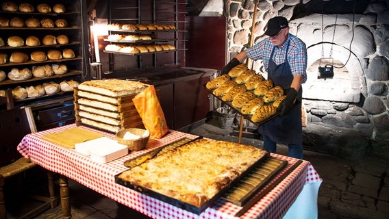 Ein Mann backt in der Bäckerei des Museumsdorf Cloppenburg Brot. © dpa Foto: Sina Schuldt