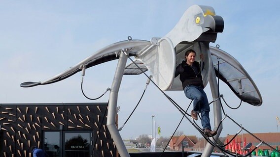 Die Leiterin des Nationalparkhauses, Sonja Wolters, testet das Klettergerüst in Form einer Kornweihe auf dem neuen Nationalparkhaus auf Norderney. © dpa-Bildfunk Foto: Hans-Christian Wöste
