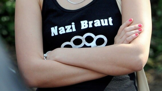 Frau mit verschränkten Armen trägt ein T-Shirt mit dem Aufdruck "Nazi Braut". © dpa - Bildfunk Foto: Carsten Rehder