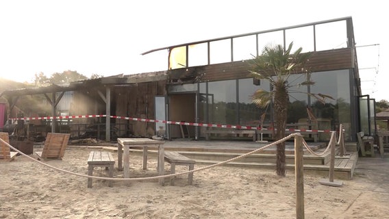 Absperrband der Polizei vor Sonnenschirmen des Beachclubs in Nethen (an einem See im Ammerland). Hier hat es einen Brand gegeben. © NDR 