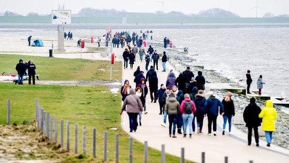 Zahlreiche Spaziergänger sind auf der Promenade am Strand von Norddeich unterwegs. © dpa-Bildfunk Foto: Hauke-Christian Dittrich