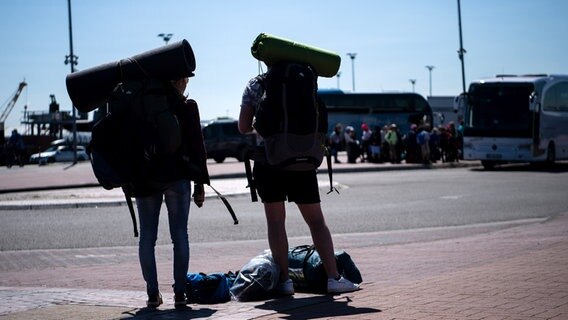 Norddeich: Reisende stehen mit ihren Rucksäcken am Hafen. © dpa-Bildfunk Foto: Sina Schuldt/dpa