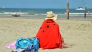 Eine Frau hat sich ein Badetuch umgeschlagen und schaut auf die Nordsee. © NDR Foto: Thomas Stahlberg