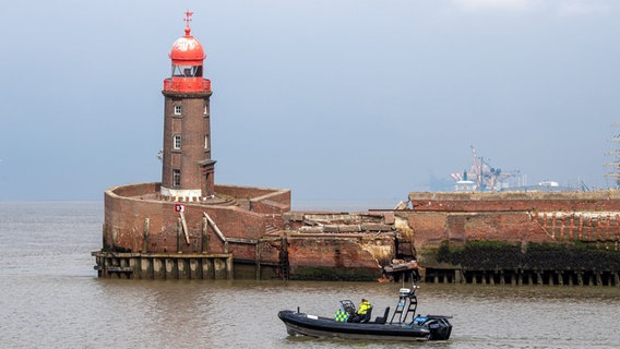 Die Wasserschutzpolizei fährt an dem schief stehenden Leutturm auf der Nordmole in Bremerhaven vorbei. © Sina Schuldt/dpa Foto: Sina Schuldt