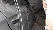 Ein Pkw steht zur Hälfte ein einem Wohnhaus, nachdem er die Hauswand durchbrochen hat. © Nord-West-Media TV 