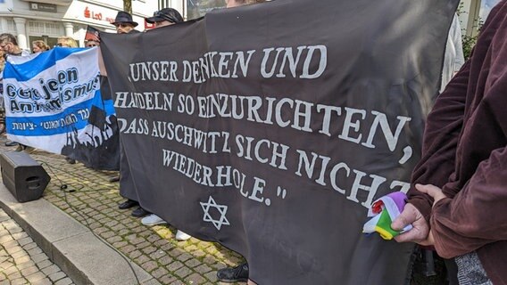 Menschen auf einer Solidaritätsdemo in Oldenburg halten ein Banner auf dem steht "Unser Denken und Handeln so einzurichten, dass Ausschwitz sich nicht wiederholte." © NDR Foto: Sebastian Duden