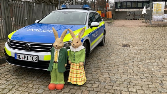 Zwei Hasenfiguren stehen vor einem Polizeiauto in Oldenburg. © Polizei Oldenburg 