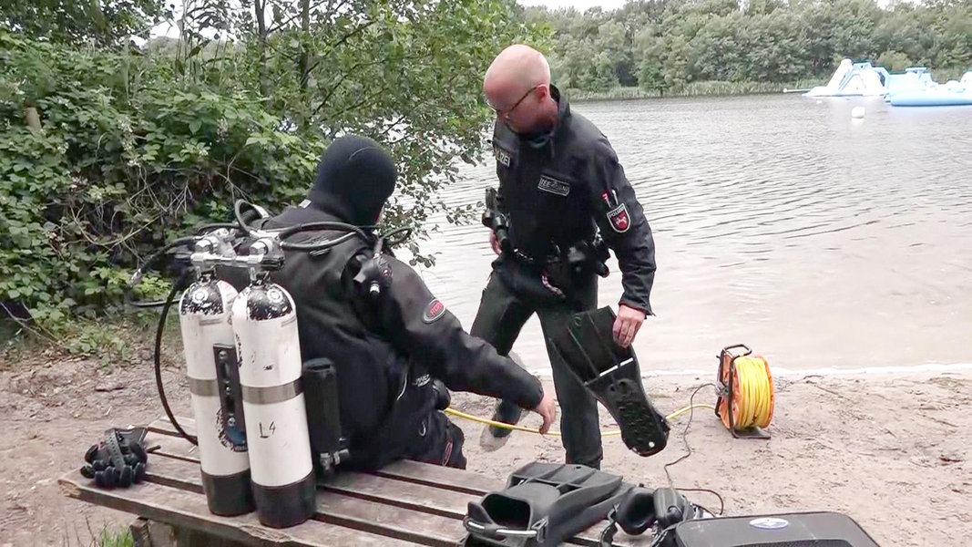 Ein Polizeitaucher und ein weiterer Polizist bereiten sich auf die Suche nach einem vermissten Stan-up-Paddler am Oyter See vor.