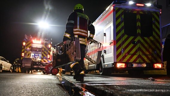 Ein Feuerwehrmann bringt Schläuche zum Einsatzort. © Lars Penning/dpa Foto: Lars Penning