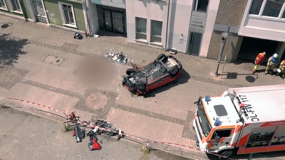 Ein Auto liegt nach einem Sturz aus einem Parkhaus auf dem Dach. © NonstopNews 