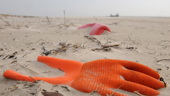 Angespülter Unrat in Form eines Arbeitshandschuhs und eines Kunststoffkanisters liegt am Strand. © picture alliance/dpa Foto: Ingo Wagner