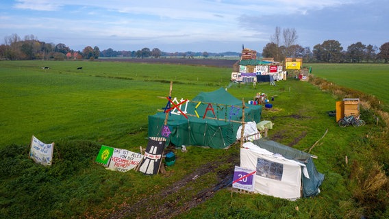 Zelte und eine Wagenburg stehen auf einem Feld, auf dem die Küstenautobahn A20 verlaufen soll. © dpa Foto: Sina Schuldt
