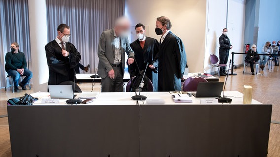 Ein Angeklagter (M) im Prozess gegen Ex-Vorgesetzte des verurteilten früheren Krankenpflegers N. Högel unterhält sich mit Anwälten im Gerichtssaal in der Weser-Ems-Hallen. © dpa Foto: Sina Schuldt