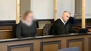 De Angeklagte (links) en advocaat Clemens Anger zitten in een rechtszaal in het Landgericht Verden.  © NDR Foto: Maren Mommsen