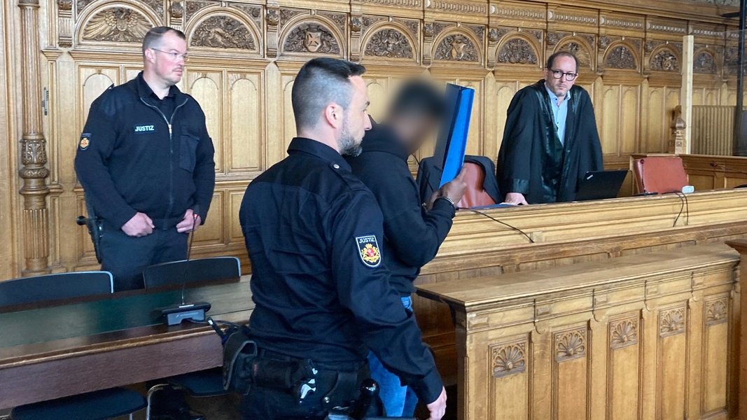 Ein angeklagter Mann wird von einem Justizbeamten in einen Gerichtssaal des Landgerichts Bremen geführt.