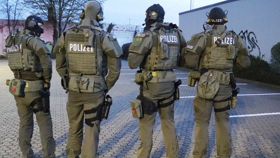 Polizeibeamte stehen in voller Ausrüstung neben einer Halle. © dpa-Bildfunk 