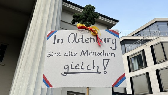 Schild mit Grünkohl darüber auf einer Demonstration in Oldenburg gegen Rechtsextremismus: "In Oldenburg sind alle Menschen gleich." © NDR Foto: Sinja Schütte