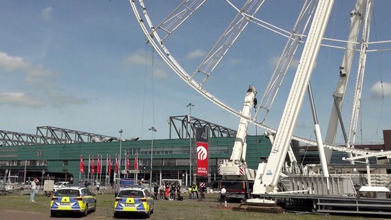 Einsatzkräfte der Polizei stehen neben einem halb abgebauten Riesenrad. © NonstopNews 