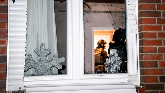 Ritterhude: Einsatzkräfte stehen hinter dem eingeschlagenen Fenster einer Wohnung. © dpa Foto: Sina Schuldt