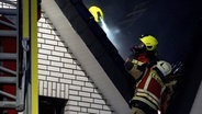 Einsatzkräfte löschen einen Brand einer Sauna in einem Dachstuhl. © TeleNewsNetwork 