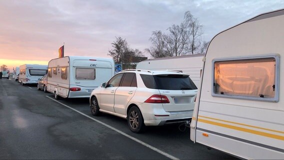 Eine Schlange von Autos und Wohnwagen im Morgengrauen. © NDR Foto: Jutta Przygoda