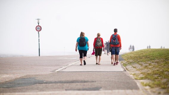 Touristen gehen im Urlaubsort Schillig an der Strandpromenade spazieren. © picture alliance / Kirchner-Media/Wedel | Kirchner-Media/Wedel 