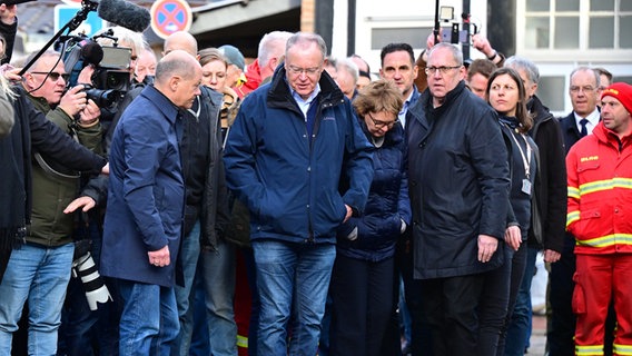 Bundeskanzler Olaf Scholz (SPD, Mitte r) und Stephan Weil (SPD, M), Ministerpräsident von Niedersachsen, besichtigen bei ihrem Besuch im Hochwassergebiet am Zusammenfluss von Weser und Aller eine überflutete Straße. © Philipp Schulze/dpa Foto: Philipp Schulze