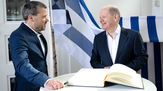 Kanselier Olaf Scholz (rechts) ondertekent het Gouden Boek van Norderney, naast Frank Ulrichs, burgemeester van Norderney.  © dpa-Bildfunk Foto: Sina Schuldt/dpa